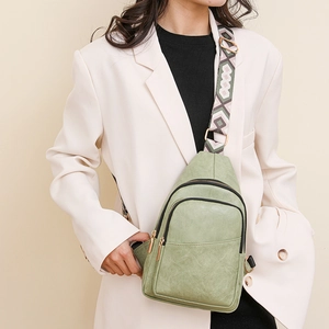 Détail du sac bandoulière en similicuir vert clair avec sangle tissée sur costume beige