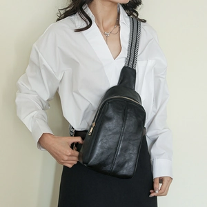 Detail of vintage black faux leather chest bag with gold zipper and geometric strap
