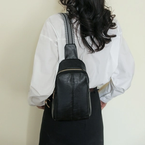 Detail view of black PU leather chest bag with chic geometric woven shoulder strap on model