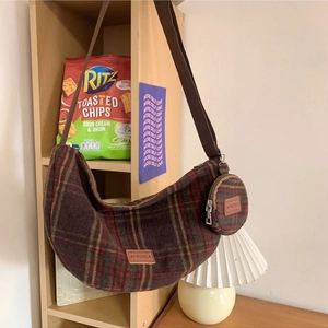 Winter plaid crossbody crescent bag with matching mini round purse on a wooden bookshelf
