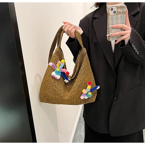 Detail of yellow knit crossbody bag featuring 3D cartoon monster charms on textured fabric