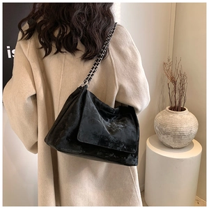 Détail d'un sac à bandoulière noir en cuir PU matelassé avec chaîne argentée sur modèle