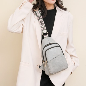 Sac bandoulière gris avec sangle tissée géométrique sur un mannequin en blazer