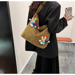 Detail of yellow tweed tote bag with colorful plush pom-poms and pearl button closure