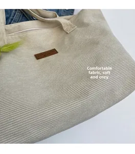 Detailed macro view of beige corduroy tote fabric featuring the brown leather logo patch