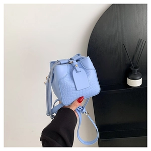Light blue mini drawstring bucket bag with crocodile texture and crossbody strap