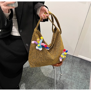 Detail view of mustard yellow tweed tote bag featuring colorful plush pom pom charm