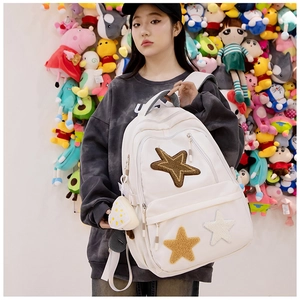 Detail view of white canvas backpack featuring star embroidery and rice ball plush charm