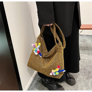 Detailed texture of mustard yellow knit crossbody bag with colorful 3D plush ball accents