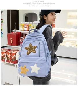Detail of lavender canvas backpack featuring plush star patches and multi-zipper structure
