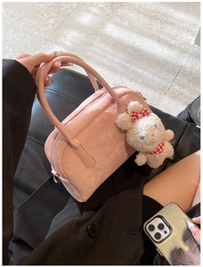 Dettaglio di una borsa Boston rosa scamosciata con un ciondolo a forma di coniglio bianco