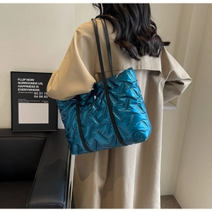 Sac cabas matelassé bleu avec bandoulières en cuir noir porté par un mannequin