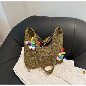 Winter tweed tote bag in tan with cartoon charm and pompom details on a leather seat