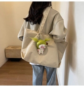 Close-up of beige corduroy tote bag with textured stripes and cartoon doll charm detail