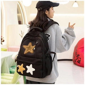 Detail of black canvas backpack featuring three gold and white glitter star patches