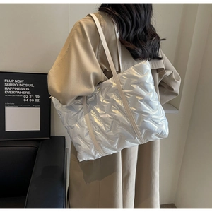 Détail du sac cabas matelassé argenté avec surpiqûres en V et sangle en cuir blanc