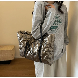 Modèle portant un grand sac cabas matelassé métallisé avec des coutures diagonales