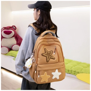 Detail view of khaki canvas backpack featuring plush star patches and cute duck pendant