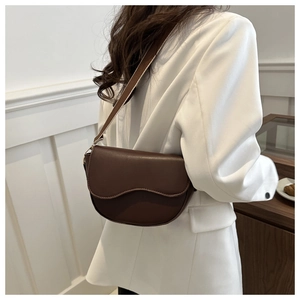 Close-up of a vintage dark brown saddle bag with wavy flap design on a model