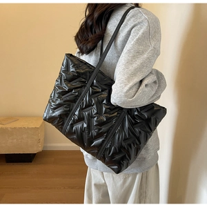Vue latérale d'un grand sac cabas noir matelassé porté à l'épaule pour la mode d'hiver