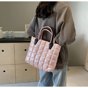 Detail of pink quilted tote bag with shiny fabric texture and black nylon straps