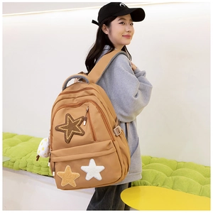 Brown canvas backpack featuring plush star patches shown on model from a side back view