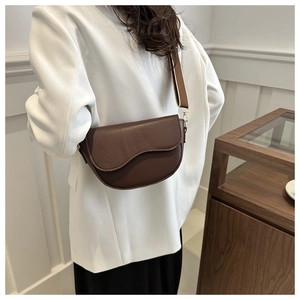 Detail of a dark brown crescent saddle bag with unique curved flap and fabric strap