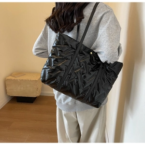 Vue arrière d'un mannequin portant un sac cabas matelassé noir dans une pièce épurée