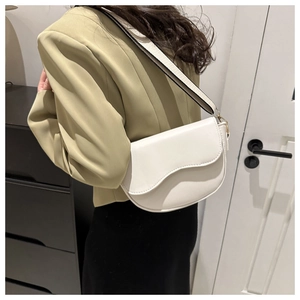 Detail of white saddle bag with wavy flap design and wide black and white strap