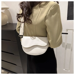 Detailed side view of off-white PU saddle bag with wide strap on olive green blazer