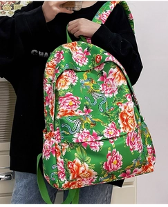 Detalle de mochila de nailon verde esmeralda con bordado vibrante de peonías y fénix