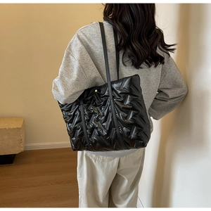 Gros plan d'un cabas matelassé noir avec texture brillante et coutures en forme de V