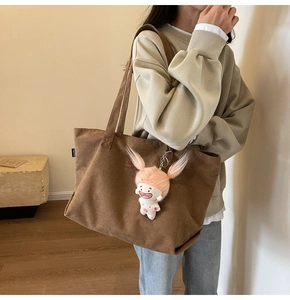 Detailed texture of brown corduroy tote bag with cute pink cartoon plush doll charm