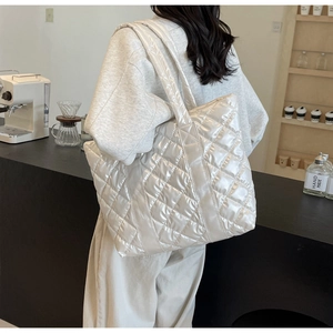Vue latérale d'un grand sac cabas matelassé en nylon blanc métallisé porté par un mannequin