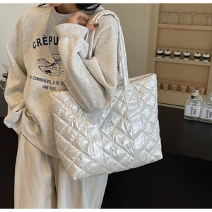 Détail d'un sac cabas matelassé blanc en tissu brillant avec surpiqûres en losanges