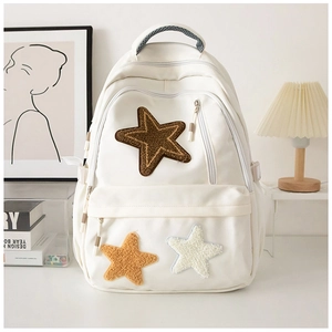 Minimalist off-white canvas backpack with colorful plush star patches in a modern interior