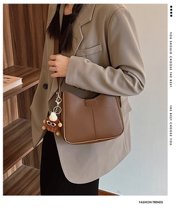 Detailed view of brown matte leather shoulder bag with a cute lion plush keychain