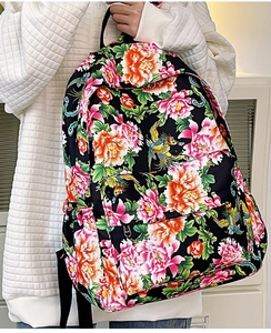 Detalle de mochila floral de nailon con fénix sobre un suéter de punto blanco texturizado
