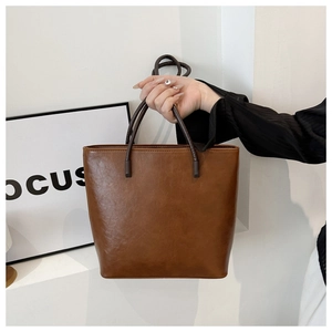 Detailed view of the brown faux leather tote bag with fine texture and slim handles