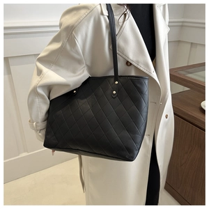 Close-up of black quilted PU leather tote bag with elegant gold rivet details