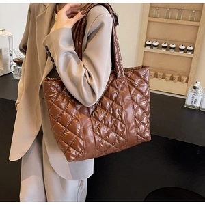 Sac fourre-tout matelassé marron brillant porté par un mannequin dans un café chic