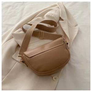 Minimalist camel PU leather saddle bag with wide fabric strap on a beige blazer background