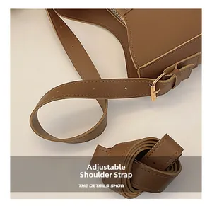 Detail of adjustable caramel brown leather shoulder strap with golden metal buckle