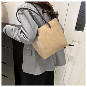 Detail view of stylish khaki PU leather tote bag with slim brown shoulder straps on a model