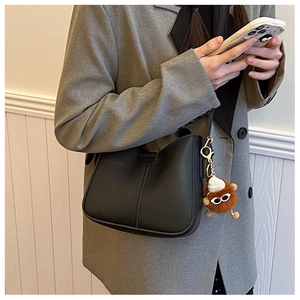Detail of black matte PU leather shoulder bag with cute brown plush doll pendant