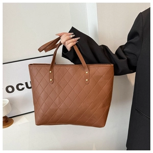 Close-up of brown quilted tote bag with matte PU texture and golden rivet handle details