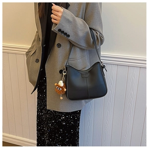 Detail view of black PU leather hobo bag featuring a unique brown plush monster charm