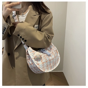 Détail de la texture en tweed, forme demi-lune et breloque pêche sur le sac à bandoulière