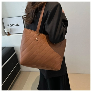Close-up of brown quilted faux leather tote bag with elegant gold rivet details