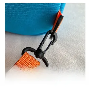 Détail de la sangle en nylon orange avec crochet pivotant en plastique noir sur sac en toile bleu